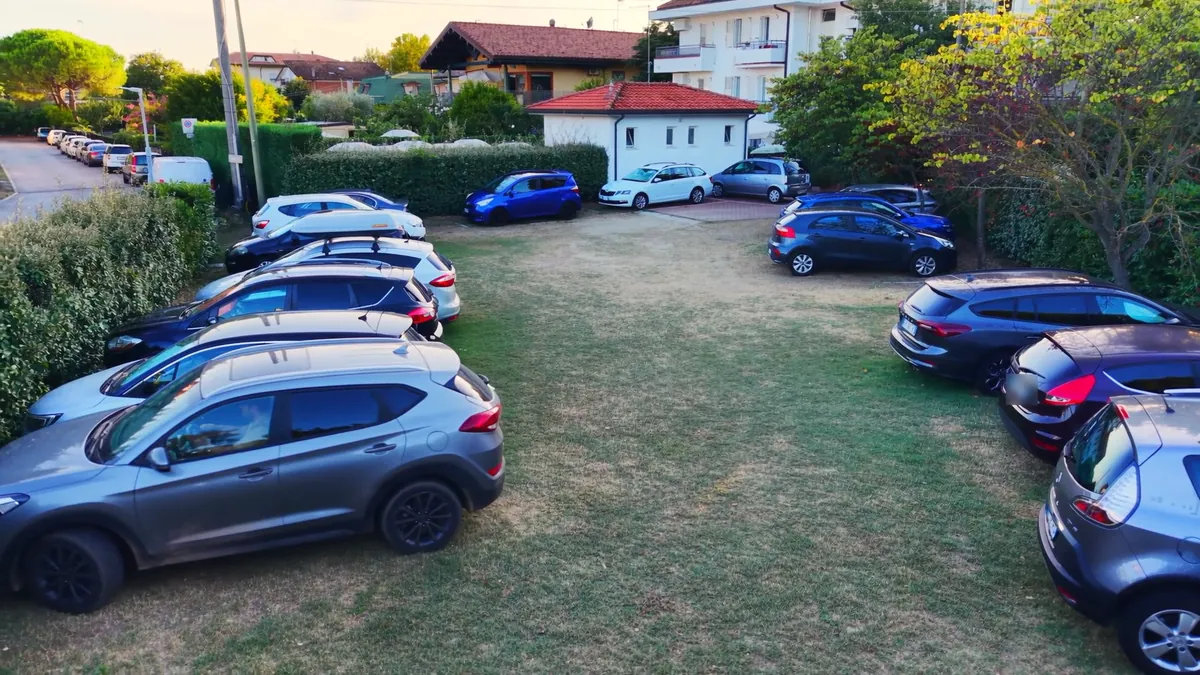Il parcheggio privato del residence visto dall'alto, con le auto degli ospiti sul prato